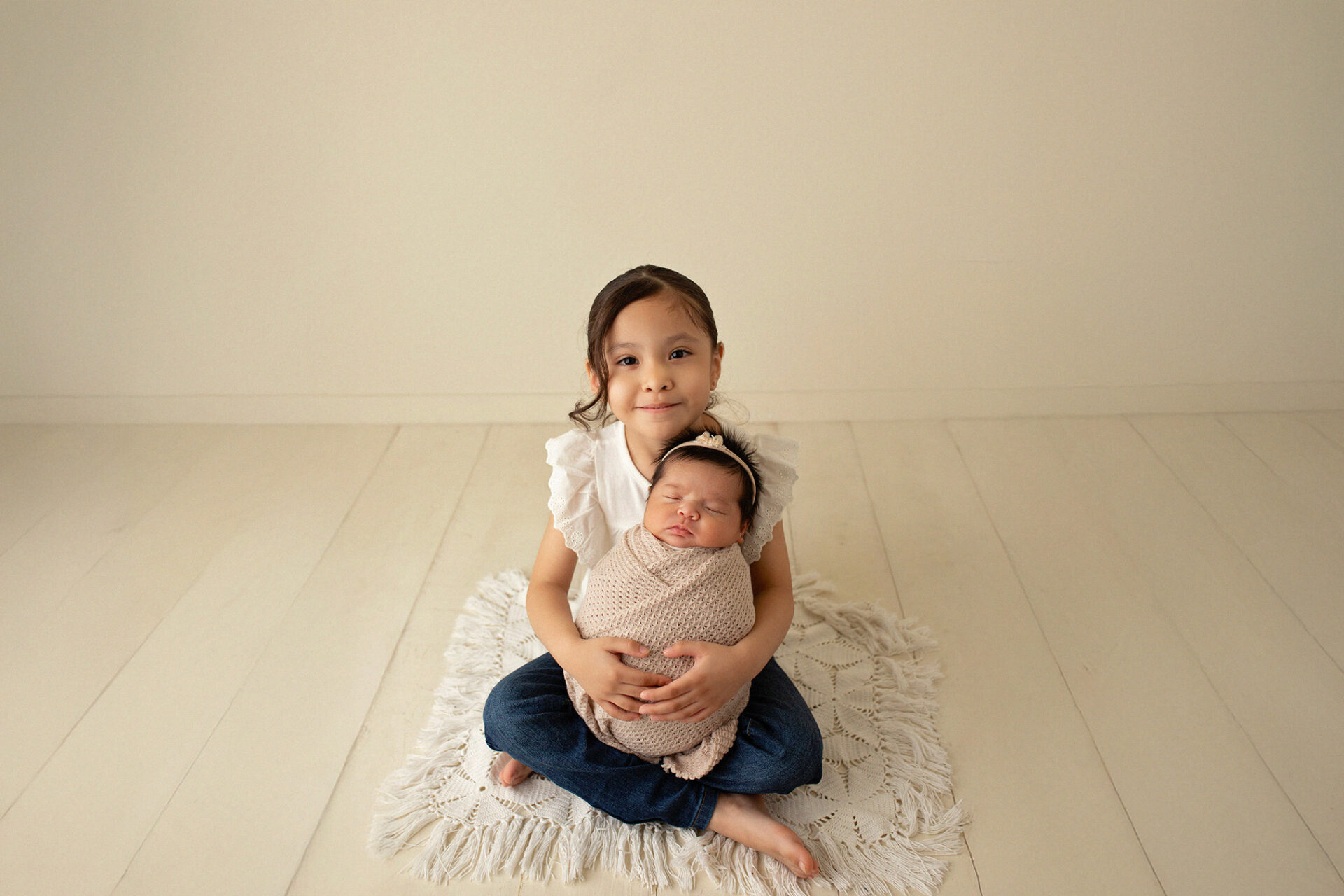 Baby posed with sister during newborn session in Ripon CA studio