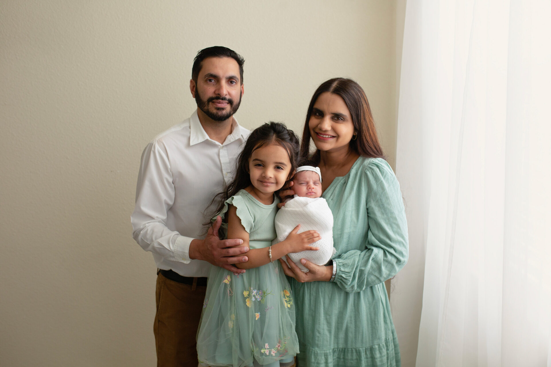 newborn baby girl swaddled in beige wrap with family manteca studio