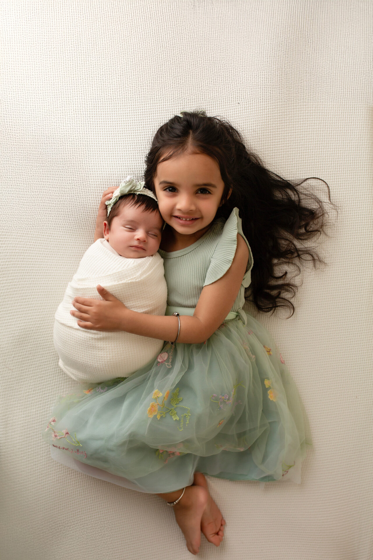 newborn baby girl swaddled in beige wrap posed on soft textured fabric in manteca studio