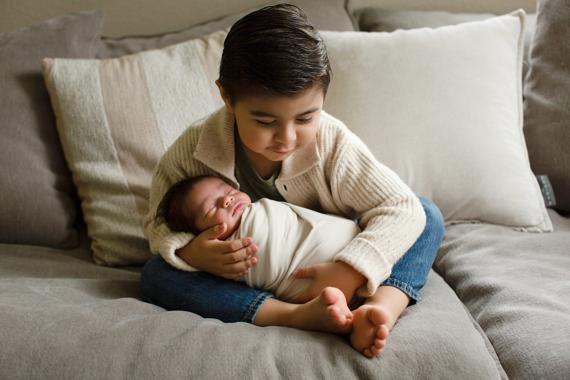 Sibling holding newborn baby during Roseville newborn session