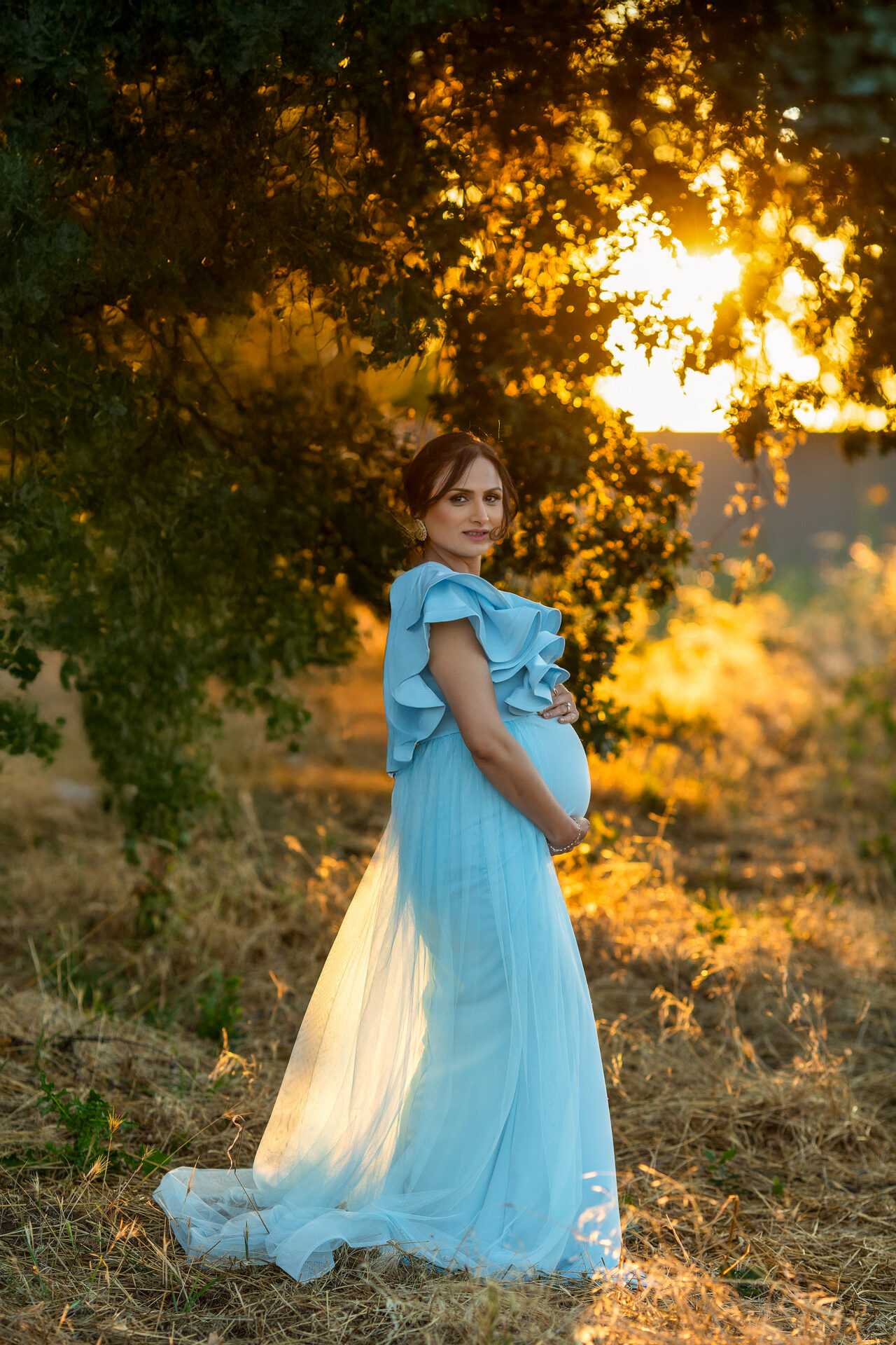 Expecting mother standing in a golden field during an outdoor maternity session in Roseville, California.