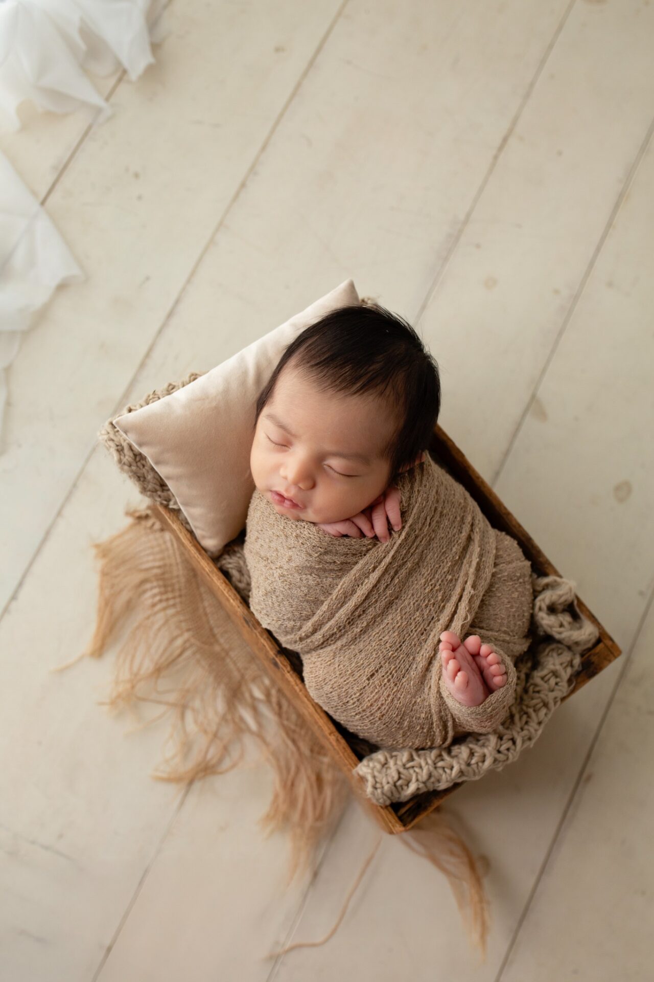 Newborn wrapped in taupe in a wooden box