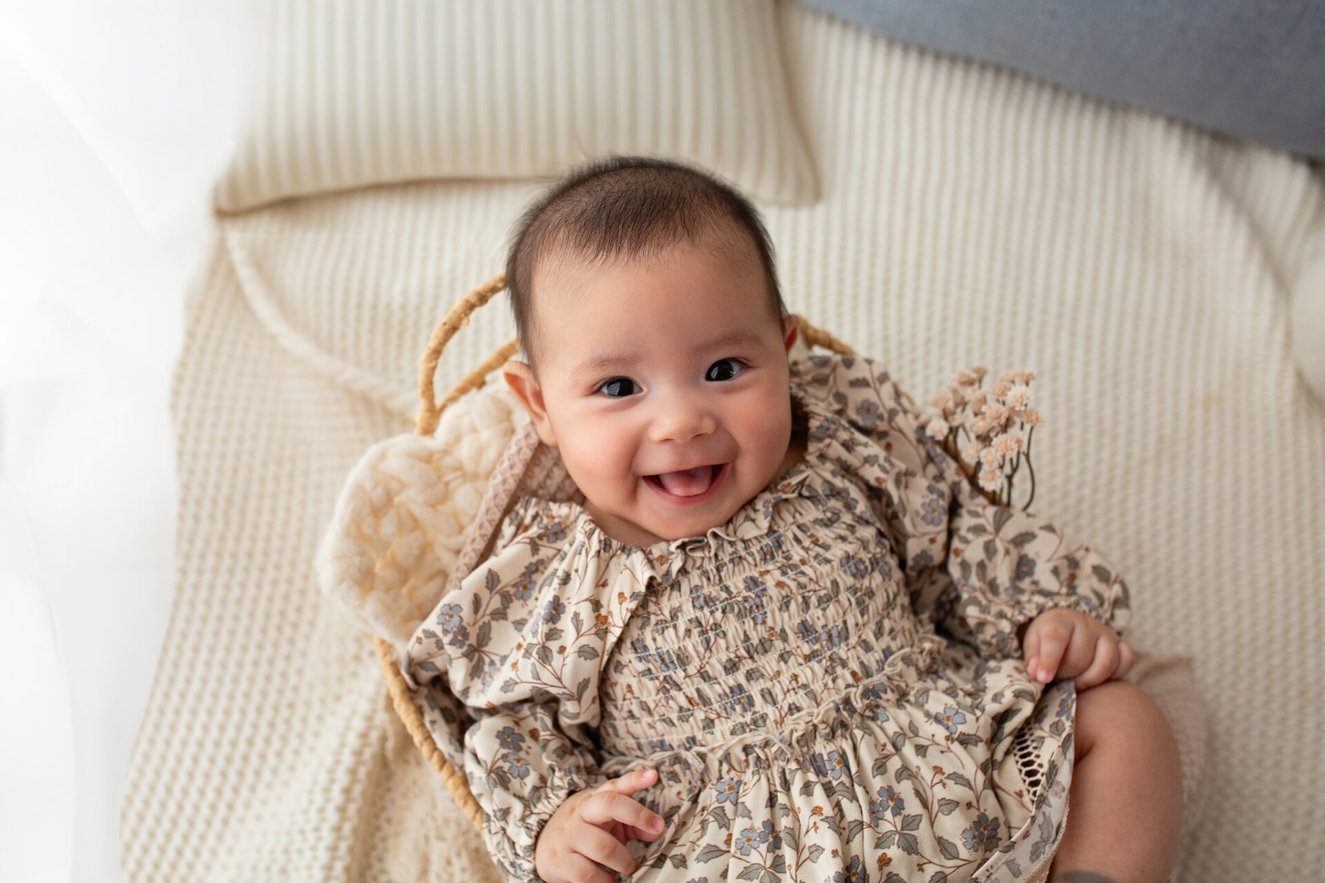 Smiling baby in a floral outfit during a milestone session
