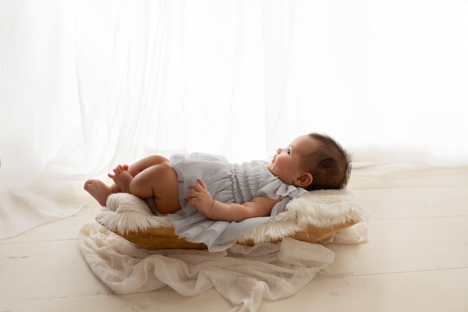 Baby reclining on a soft cream blanket in the studio